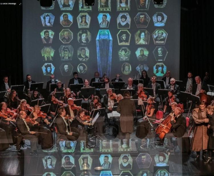 Polska Opera Królewska wykonuje "Straszny dwór" Moniuszki, artyści ubrani są w kolorowe stroje z epoki, orkiestra akompaniuje ubrana w czarne stroje
